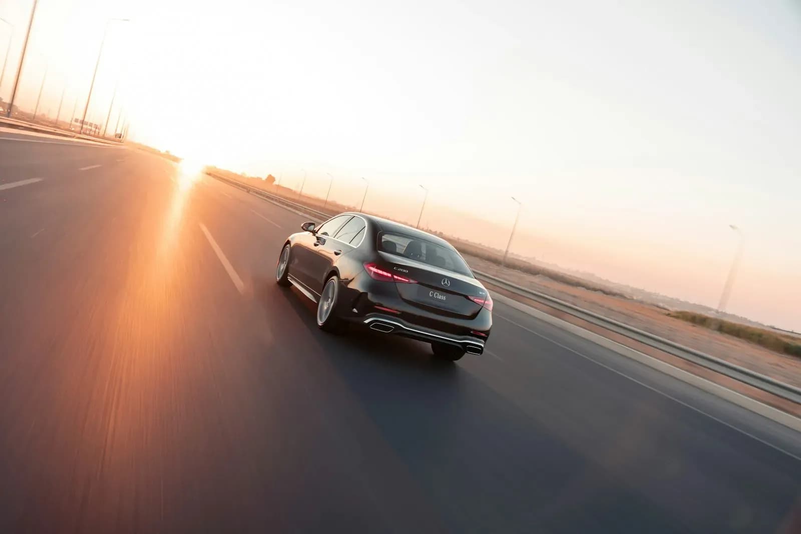 A car driving on an open road at sunset